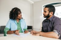 An older doctor and her young male patient are consulting