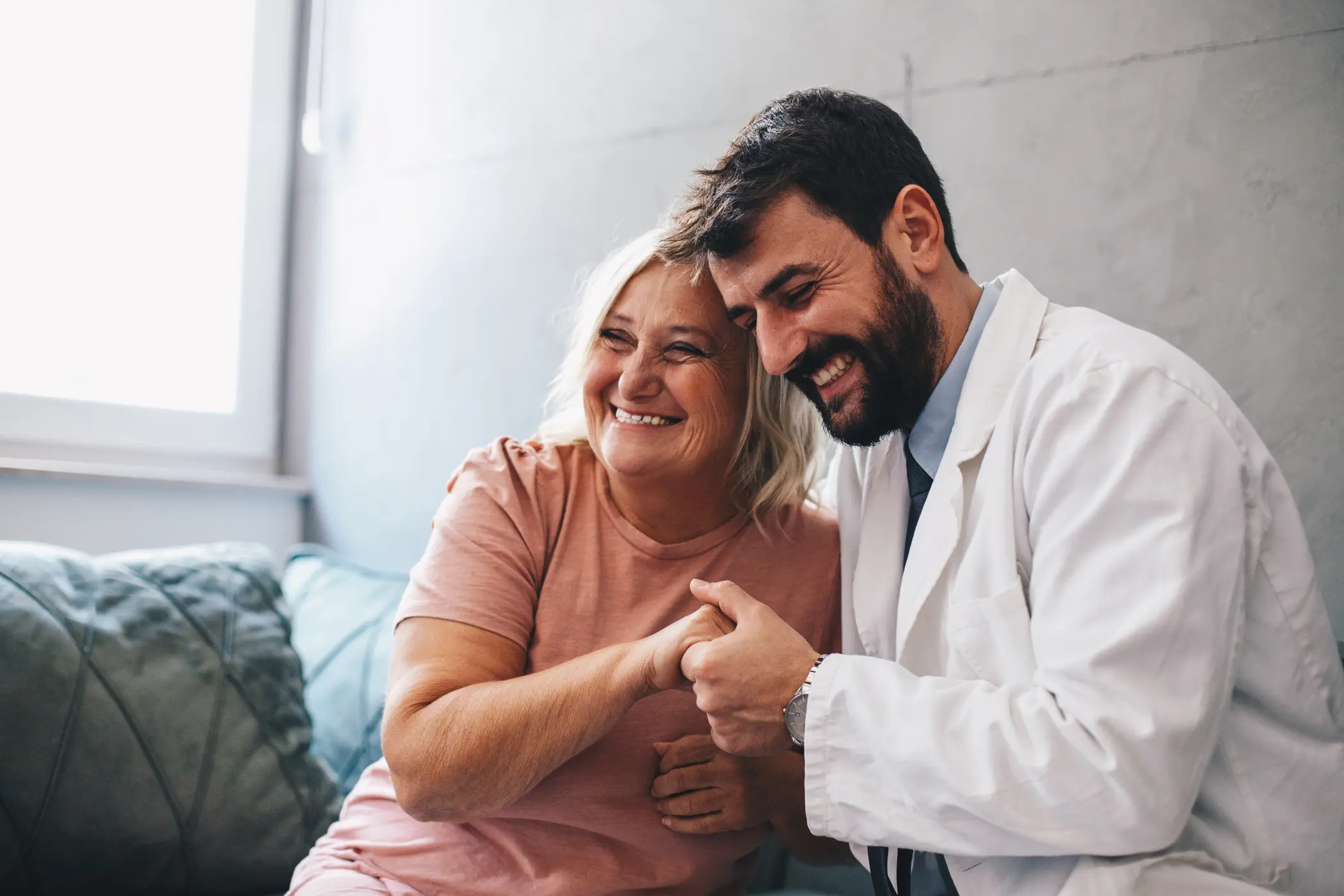 Young male doctor hugs senior patient